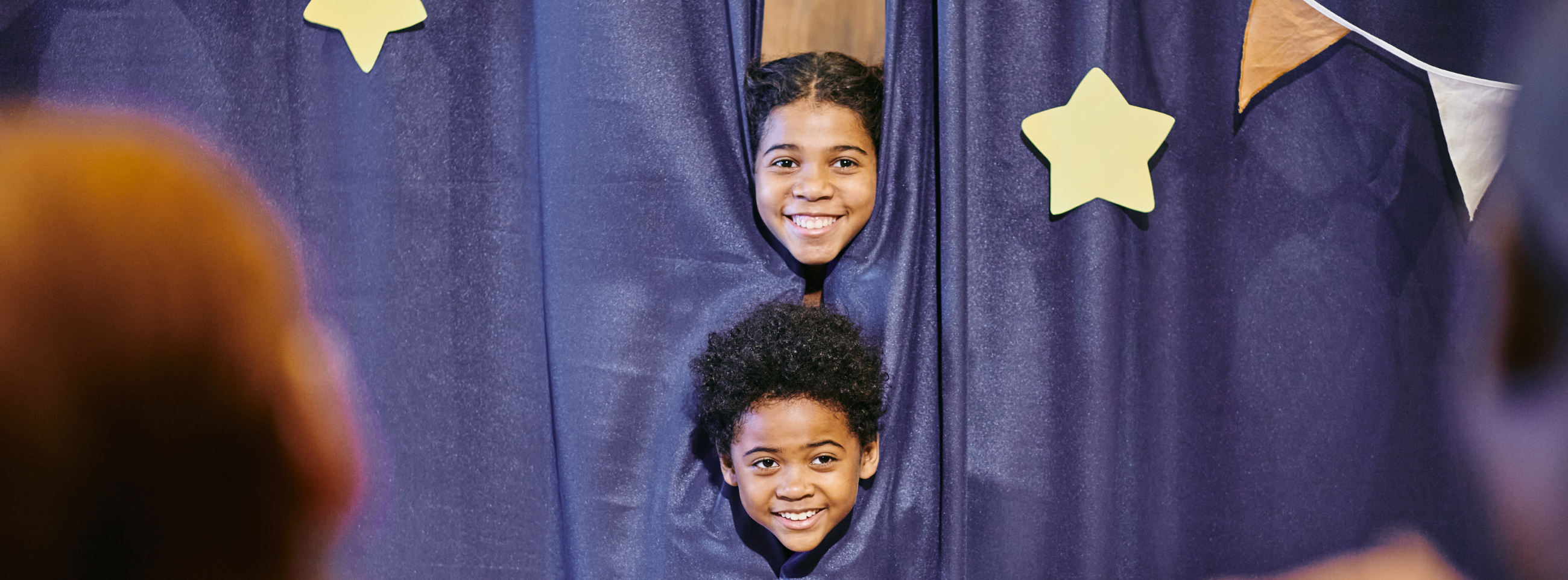 Children on stage behind a curtain